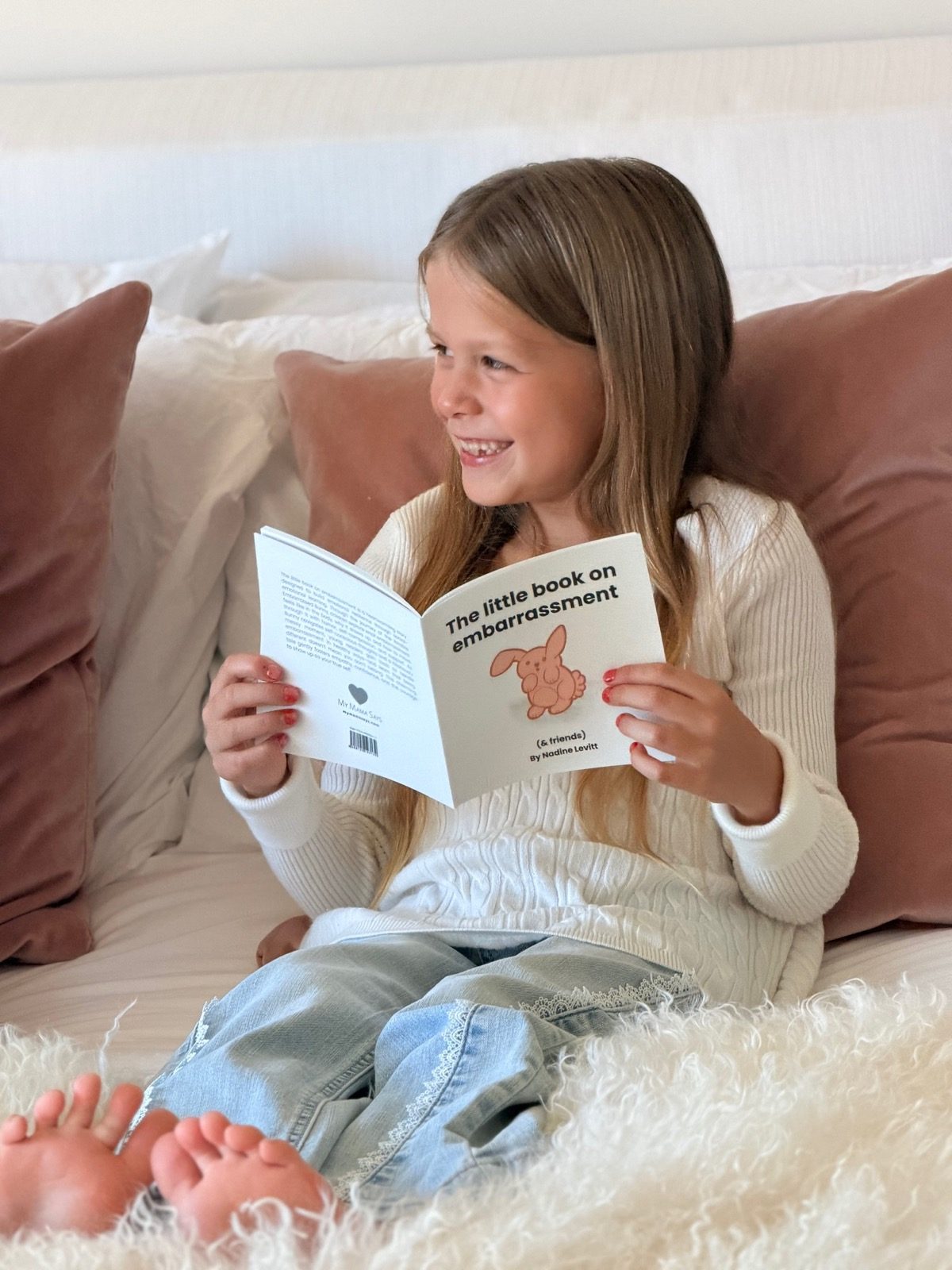 Girl smiling while reading the little book on embarrassment