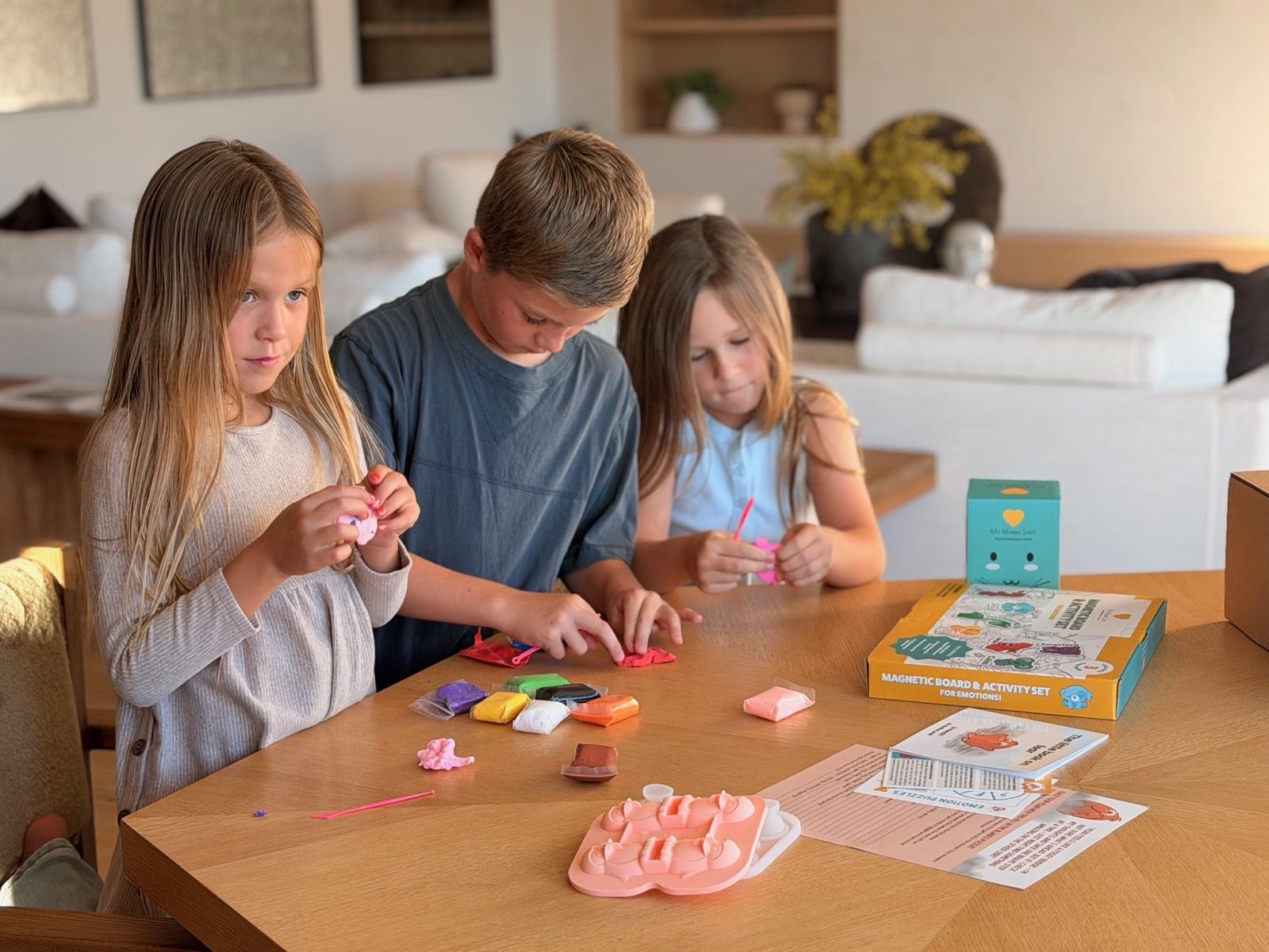Three kids playing with the clay from the fear kit at the kitchen table