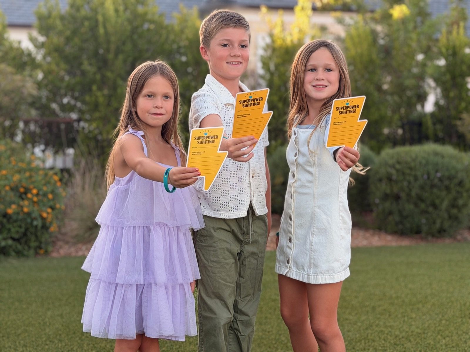 Three children holding up their Superpower Sighting thunderbolts