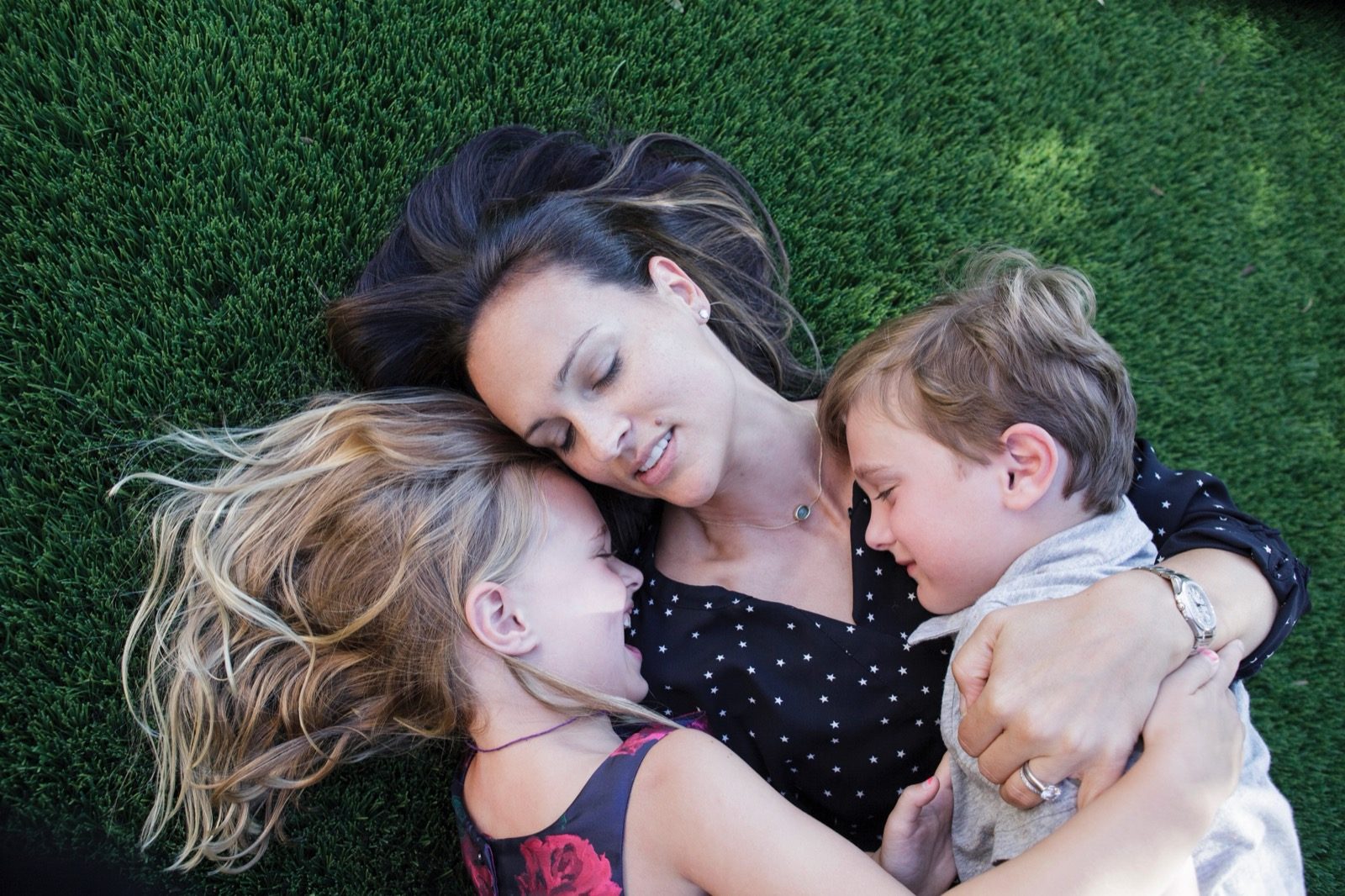 Mom hugging her two children on the grass