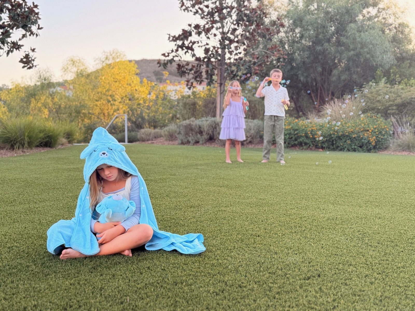 Girl in the sad pup hooded towel sitting on the lawn