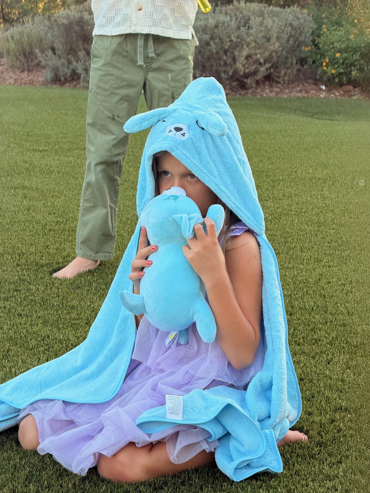 Girl wrapped in the sad pup hooded towel holding the sad pup plush