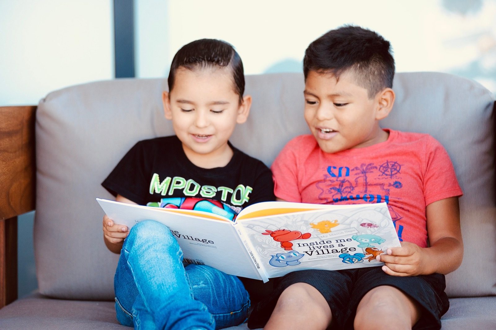 Two kids reading a My Mama Says book together on the couch